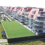 Een foto uit vogelperspectief van kunstgras die geplaatst is door het kunstgrascentrum bovenop garages bij appartementen in Nieuwpoort.