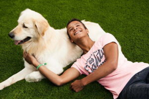 Een hond en persoon die samen liggen te genieten op het kunstgras aangelegd door het kunstgrascentrum.