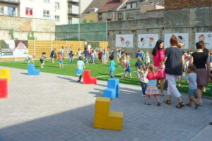 Op de foto zie je enorm veel kinderen en verschillende leerkrachten die allemaal op het kunstgras staan en spelen in op de school aangelegd door het kunstgrascentrum.