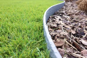 Een close up van kunstgras en afboording van een plantenvak in de kunstgras kijktuin te Lauwe