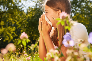 Kind die last heeft van hooikoorts in de tuin.